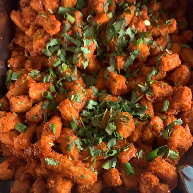 Close-up of Kathmandu Restaurant's crispy orange chicken, garnished with fresh cilantro and green onions.